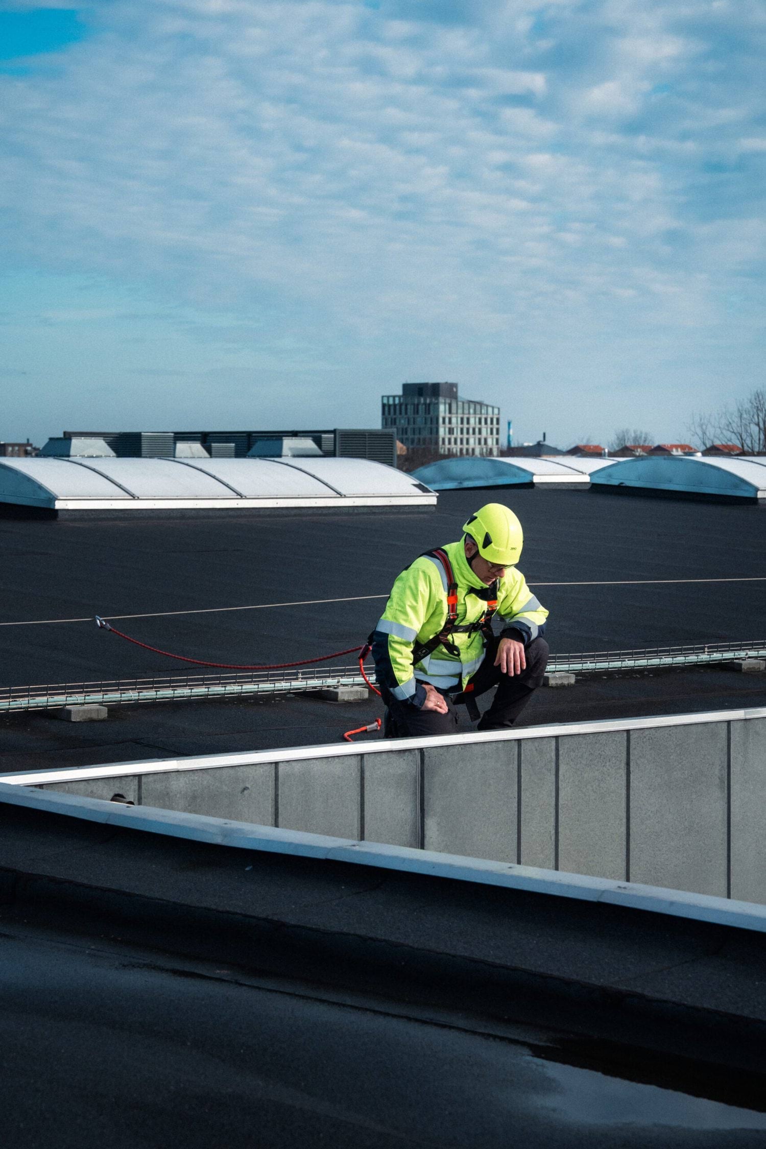 Medarbejder med faldsikring arbejder ved tagkant på fladt tag