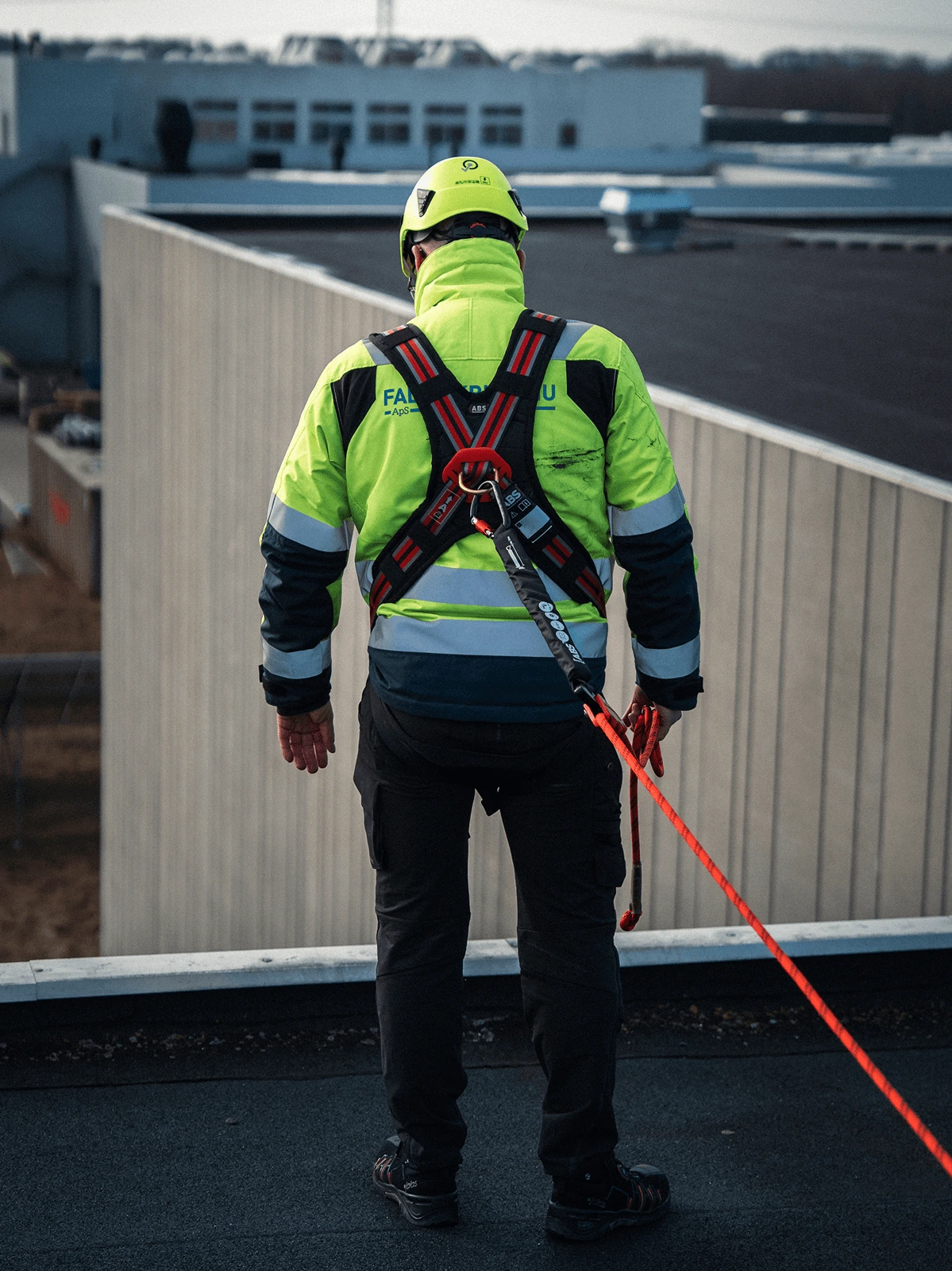 Medarbejder med sikkerhedssele og faldsikringsline under arbejde på tag